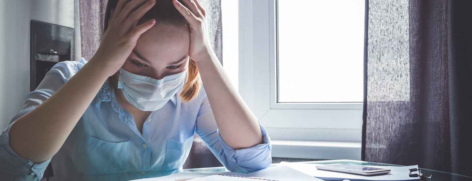 woman wearing face mask and looking at bills