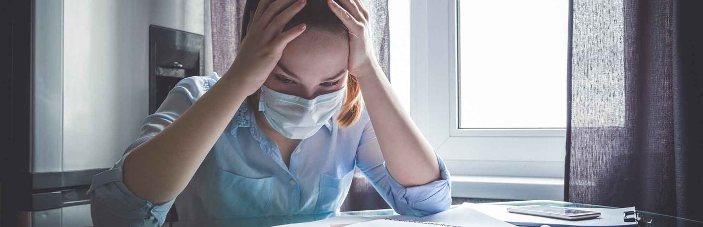 woman wearing face mask and looking at bills