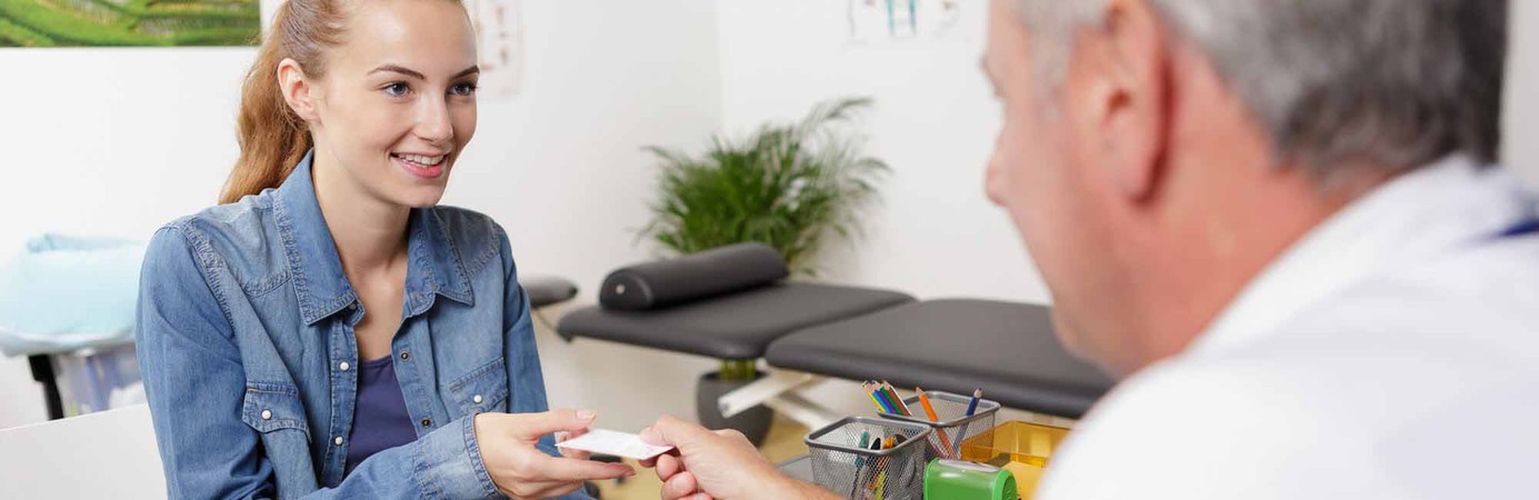 Woman handing her health insurance ID card to a healthcare professional