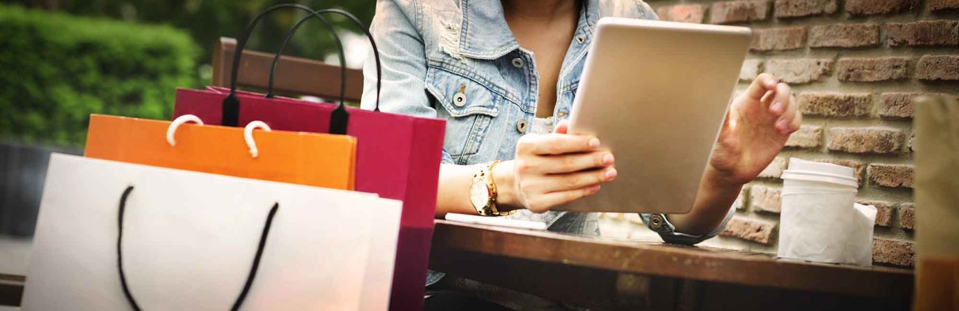 Person sitting with coffee cup, tablet and shopping bags