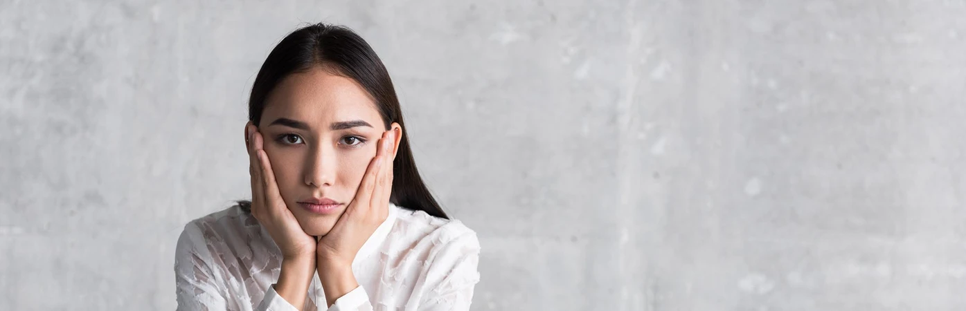 woman with disappointed expression holding hands under her chin